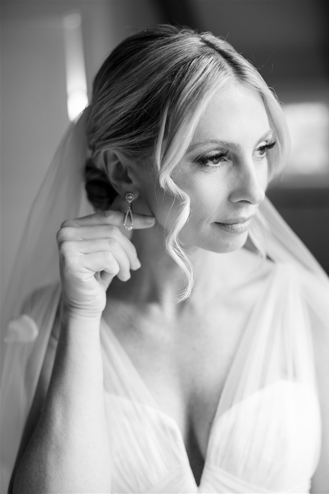 black and white photography of bride fixing her earring accessory. Photo by Vanessa Joy Photography.
