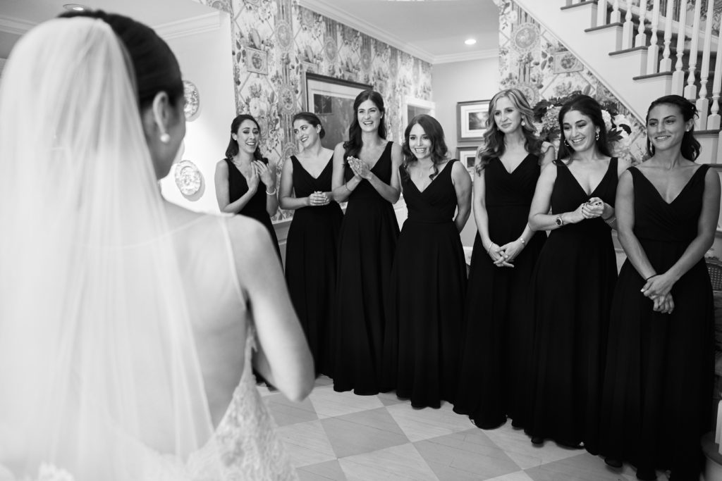 bride reveal with emotional bridesmaids in black dresses. Photo by Vanessa Joy Photography