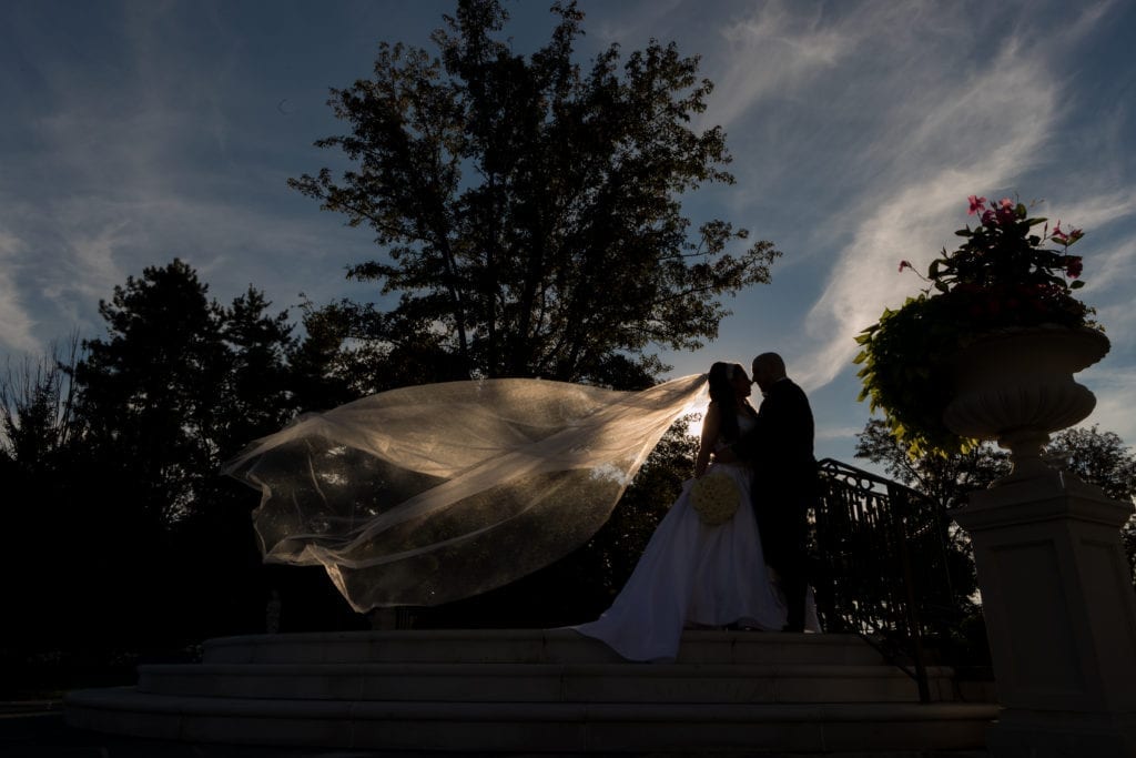 Bride and groom at dusk in her Pnina Tornai with her veil blowing