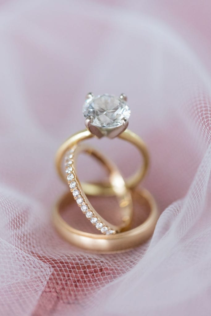 detail shot of wedding bands and round solitaire engagement ring