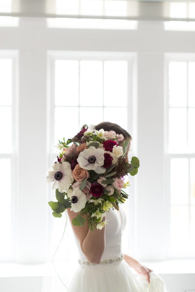 bride holding Cassandra Shah Flowers and Event Design bouquet in front of face