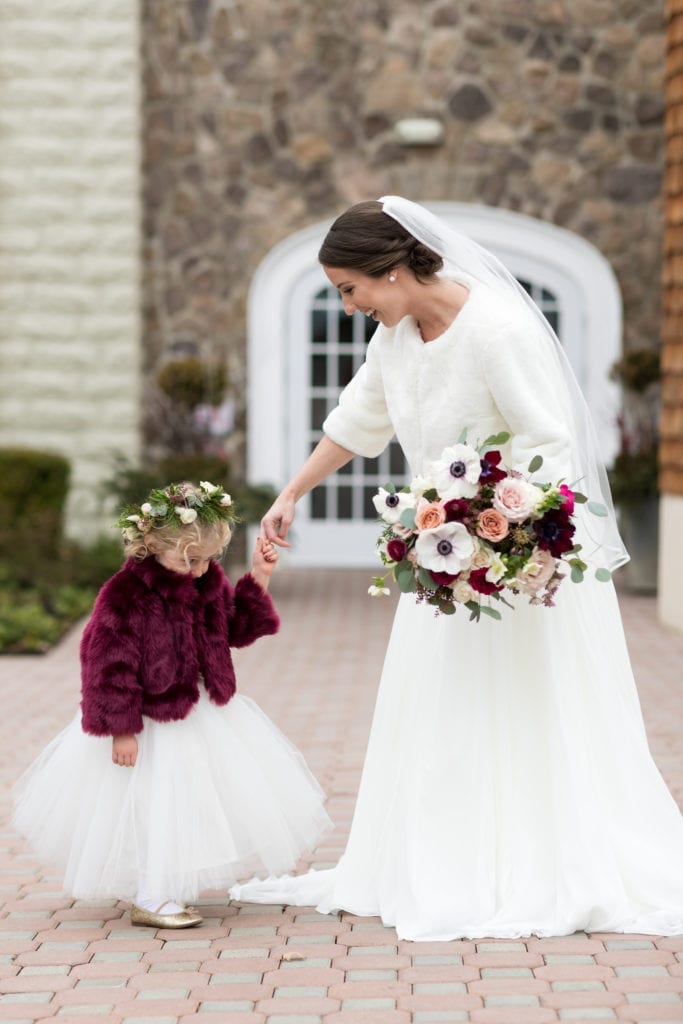 bride outside with her flower girl in their fur stoles