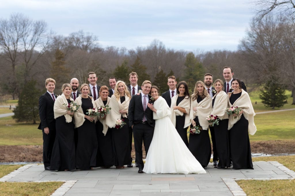 bride and groom with their wedding party outside in the cold