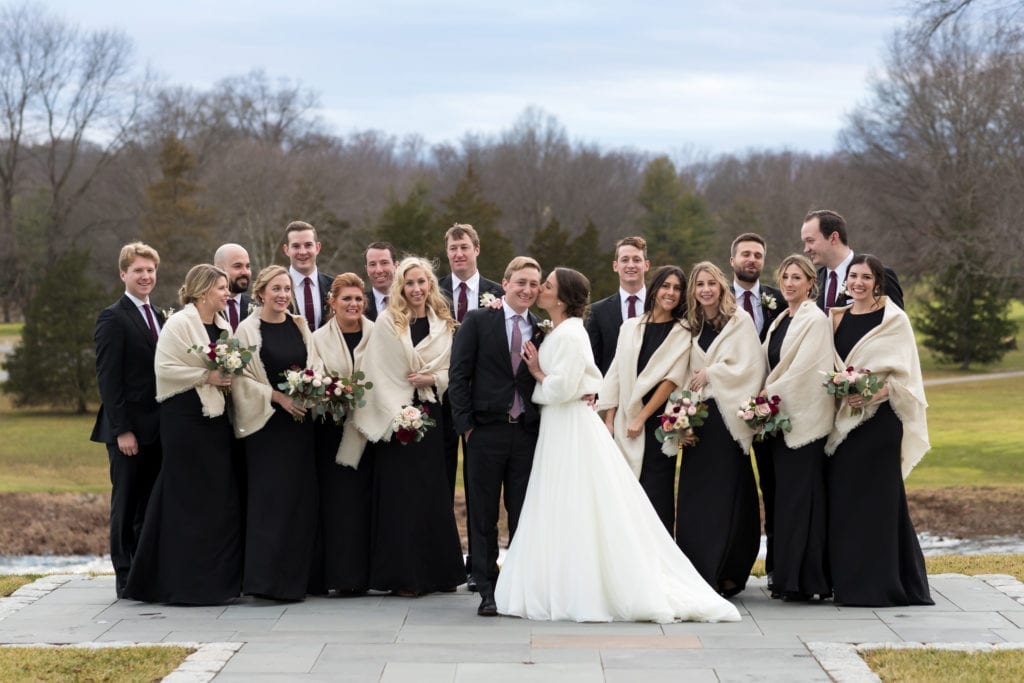 bride and groom with their all black wedding party with their tan shrugs