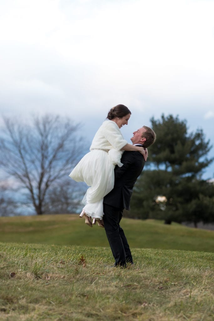groom picking up his wife on the fiddler elbow country club grounds