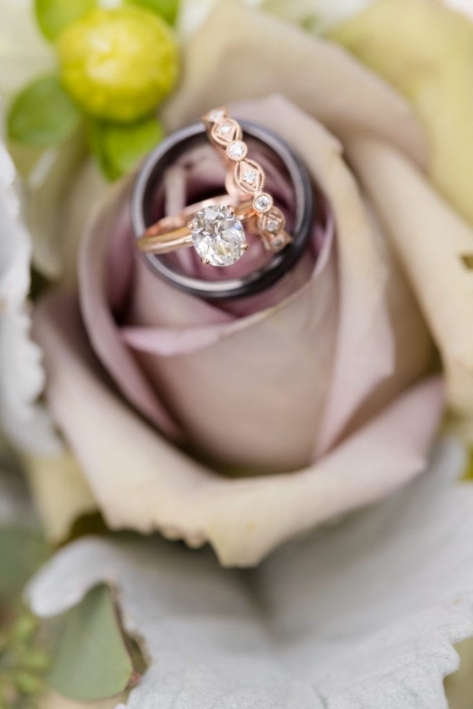 round solitaire diamond with rose gold band and wedding bands on lavender roses