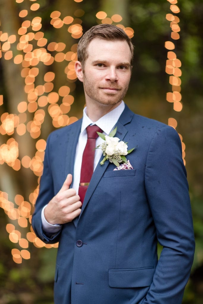 groom in front of the lighted tree 