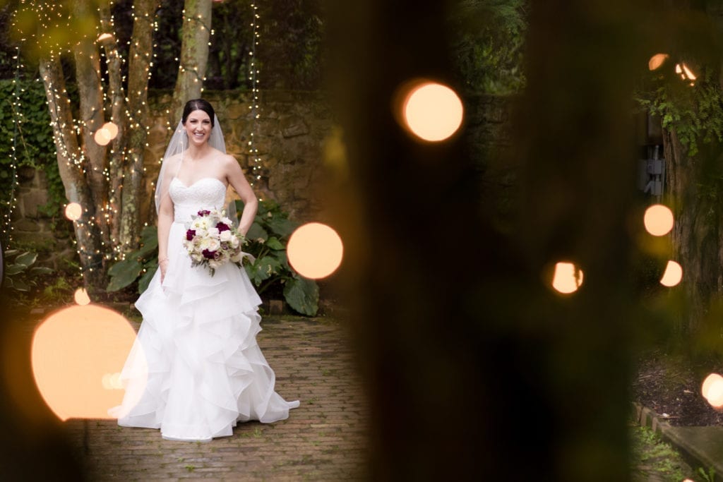 bride posing in front of lighted tree in courtyard at holly hedge estate