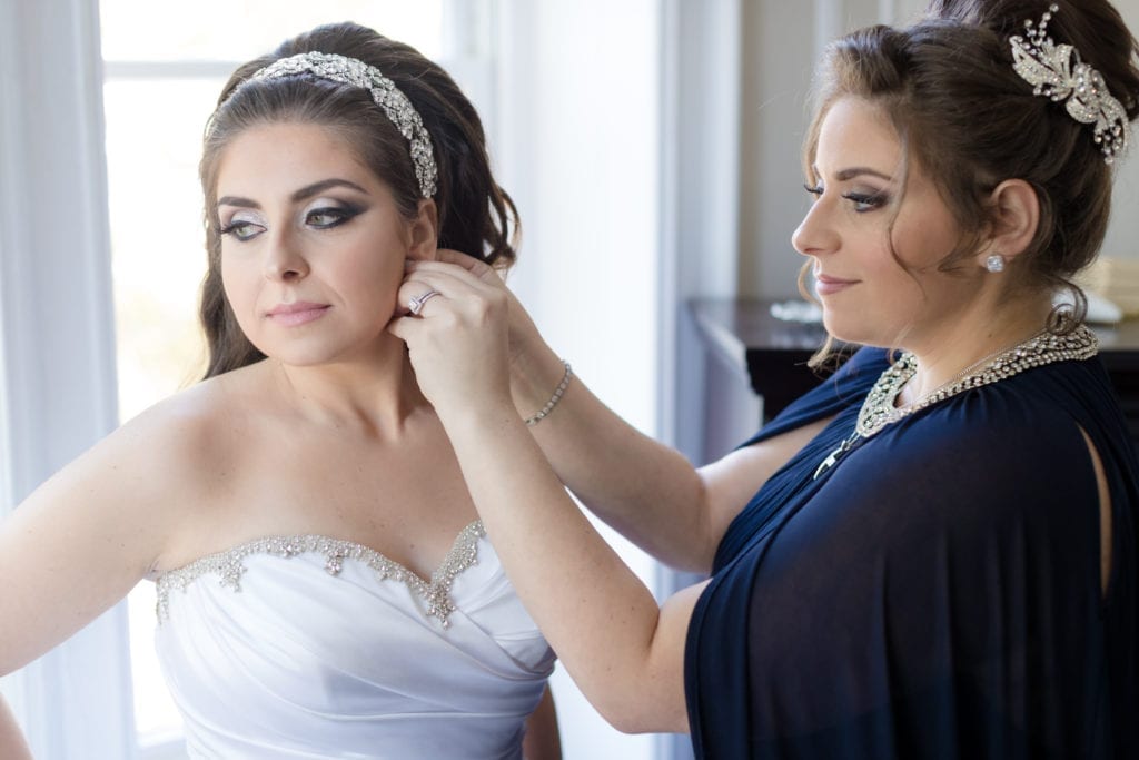 family of the bride helping her put on her diamond earrings