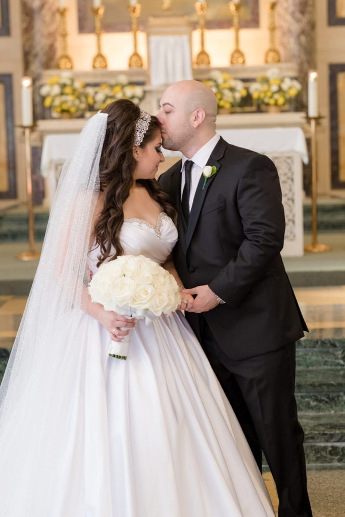 groom kissing his wife on the forehead