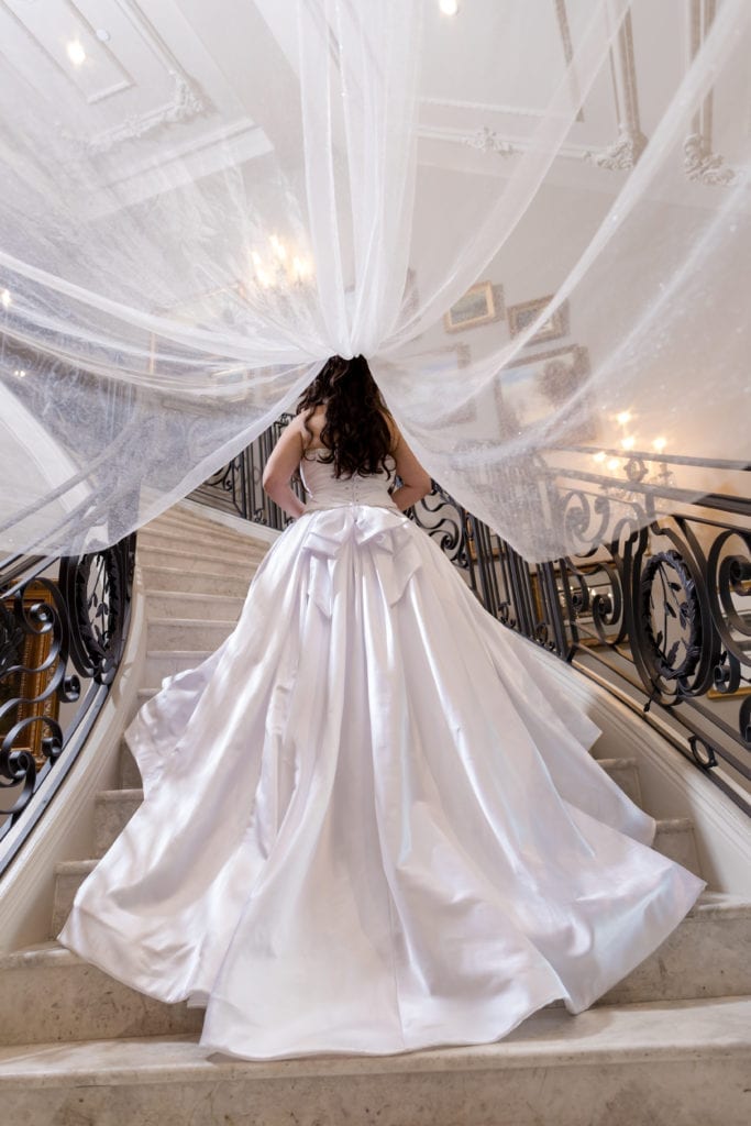 bride walking upstairs in her Pnina Tornai dress with veil flowing