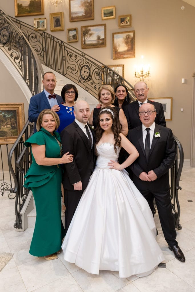 bride and groom posing with family at park chateaus grand staircase