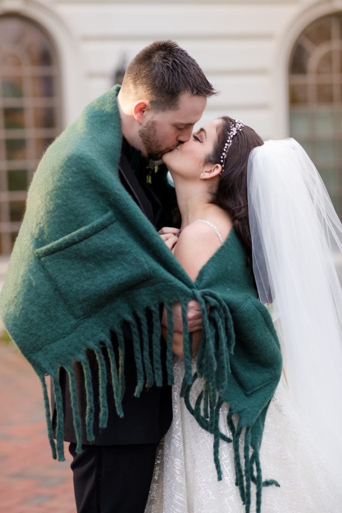 bride and groom sharing a kiss under a blanket