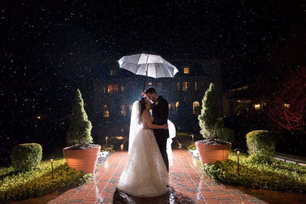 bride and groom standing in the rain with umbrella