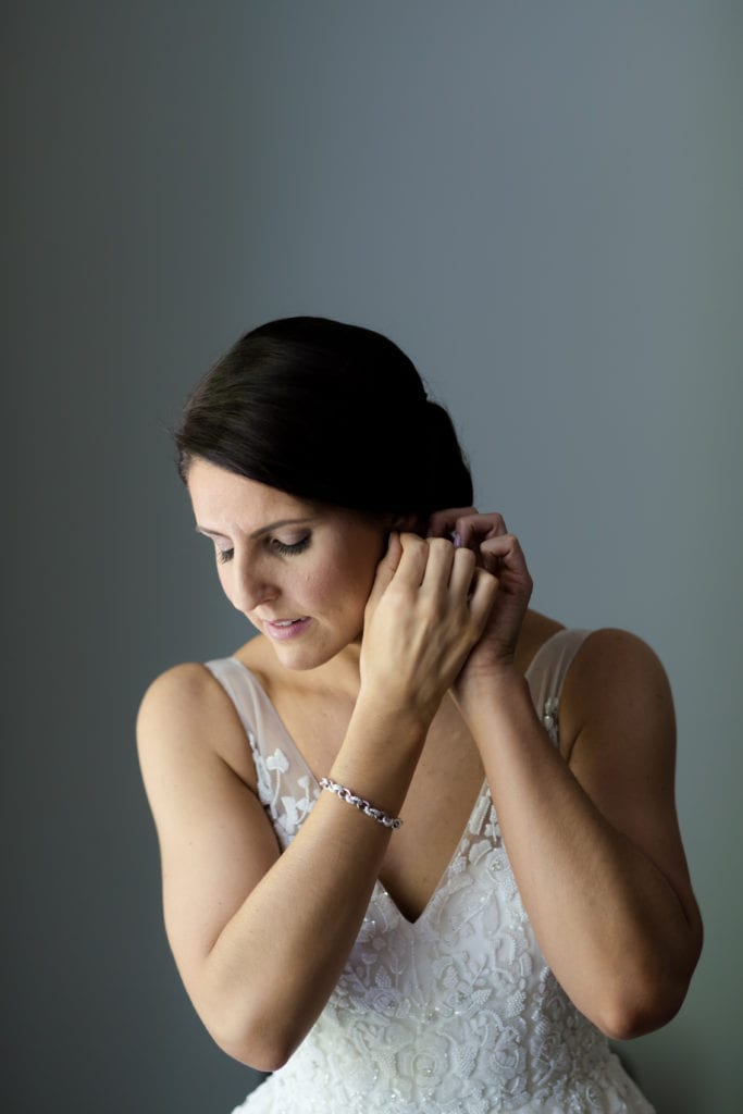 bride putting on her earrings, Vanessa Joy Photography