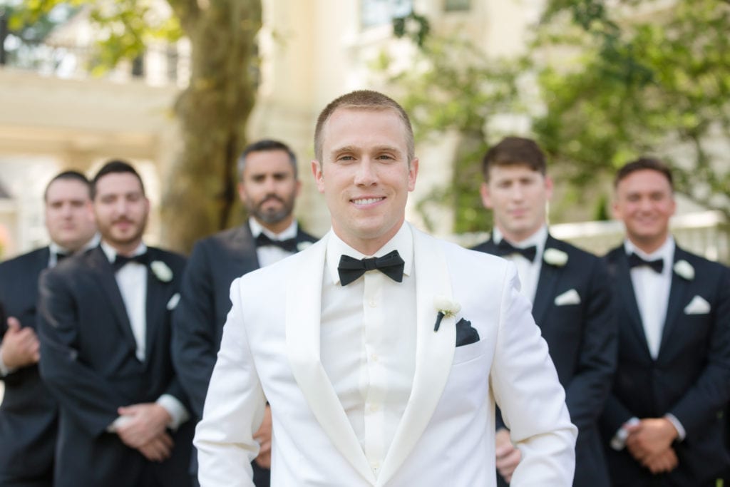 groom in the forefront of his groomsmen, groom smiling on his wedding day