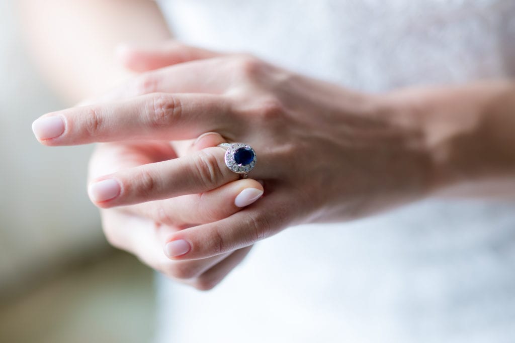 bride putting on her engagement ring, blue sapphire