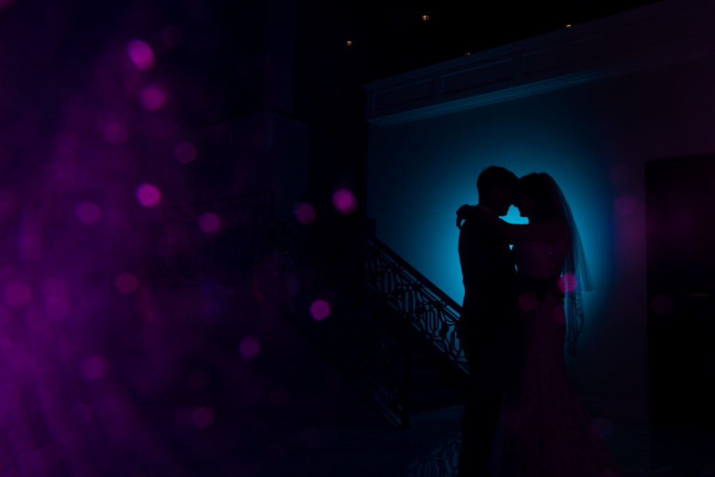 creative colored lights and gel flash of bride and groom's silhouette by staircase. Photo by Vanessa Joy photography.