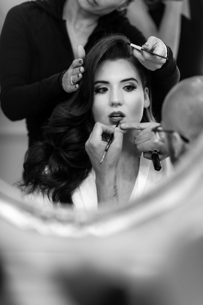 black and white photography of bride getting makeup done. Photo by Vanessa Joy Photography.
