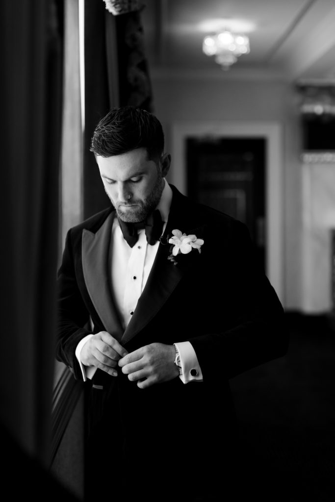 Groom buttons up suit, groom's preparations