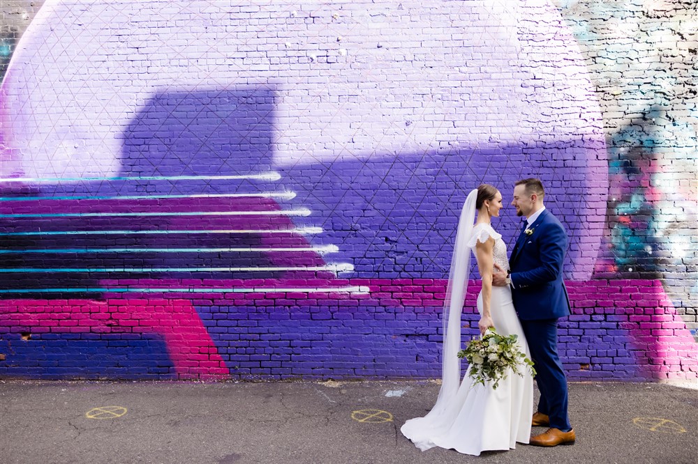 bride and groom couple in front of purple mural in jersey city, new jersey